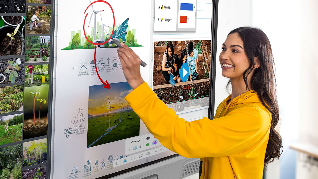 A student in a yellow hoodie interacting with a SMART Board, annotating a sustainability lesson.