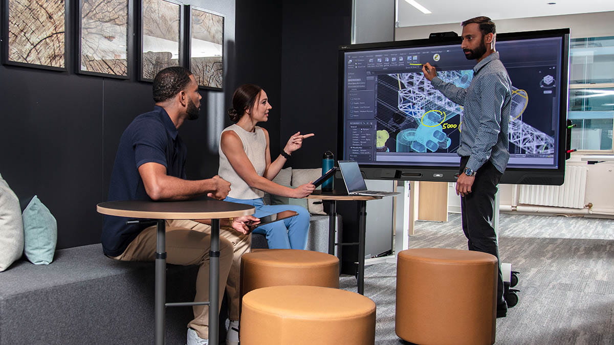 A team of three professionals collaborating around a SMART interactive display showing architectural design plans.